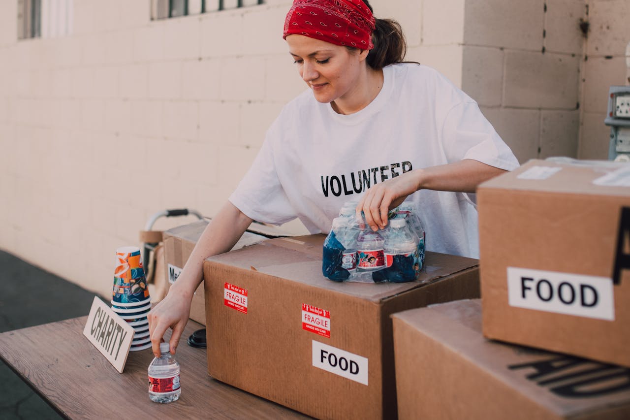 services-02 Woman volunteer sorting food and water for charity distribution at aid center.