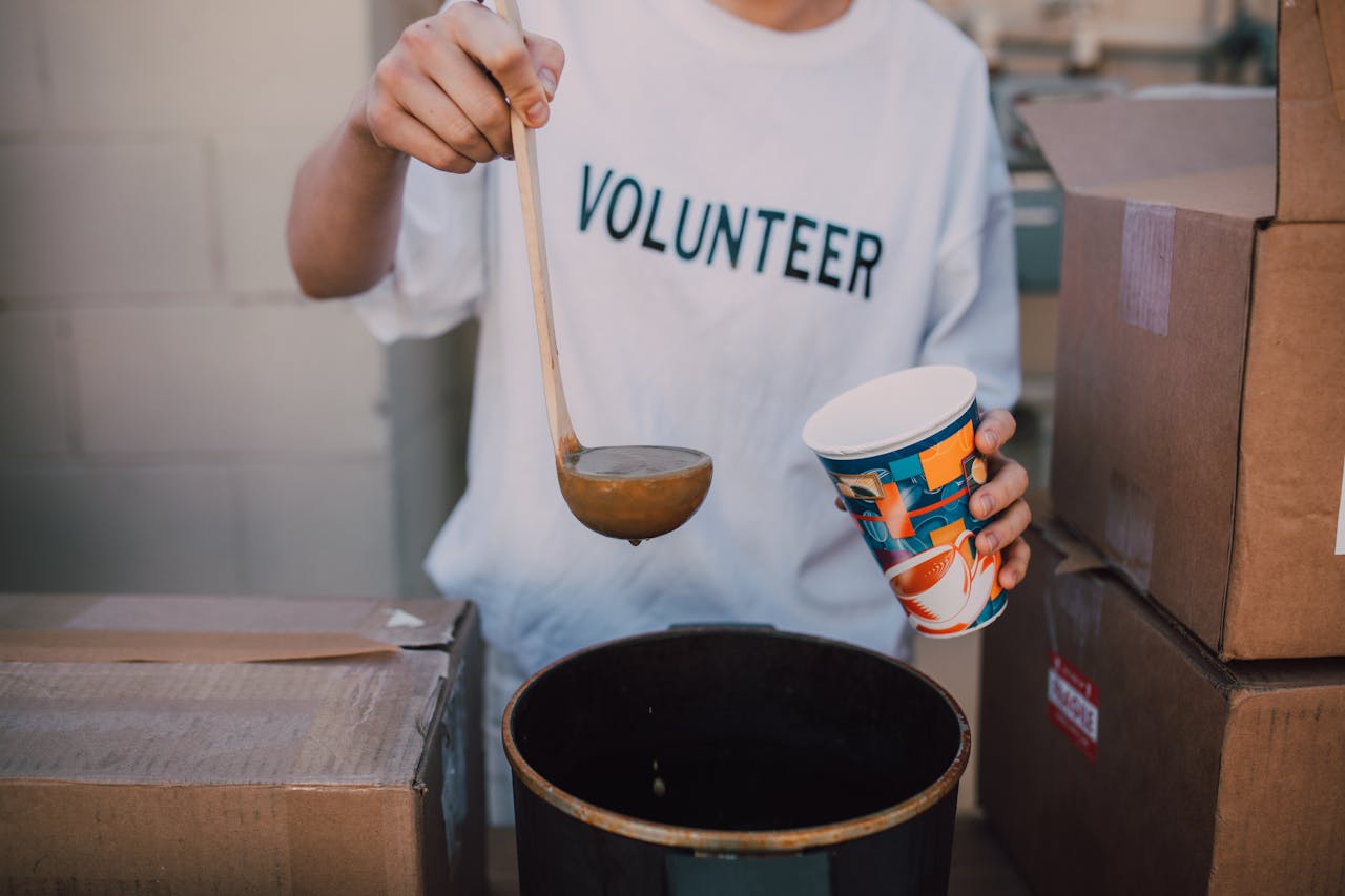 about-01 A volunteer in a t-shirt serving soup at a community event. Helping hand.